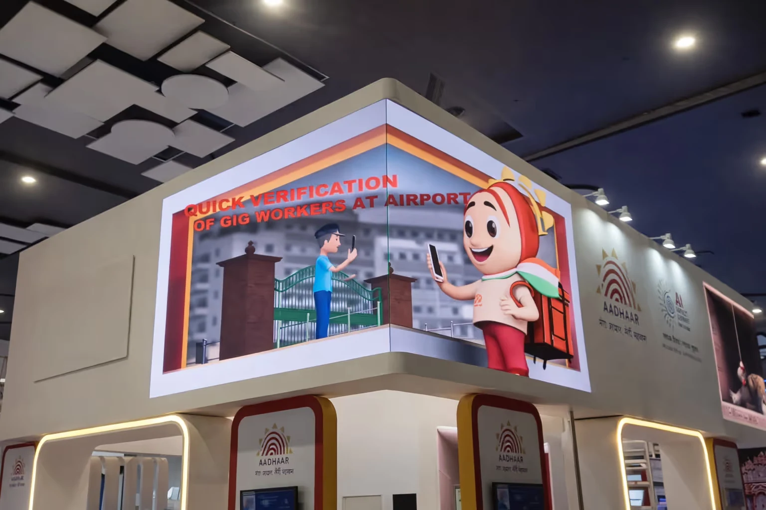 Smart digital display at an exhibition corner promoting quick verification of gig workers at airports with graphics of a person and a delivery mascot holding smartphones.