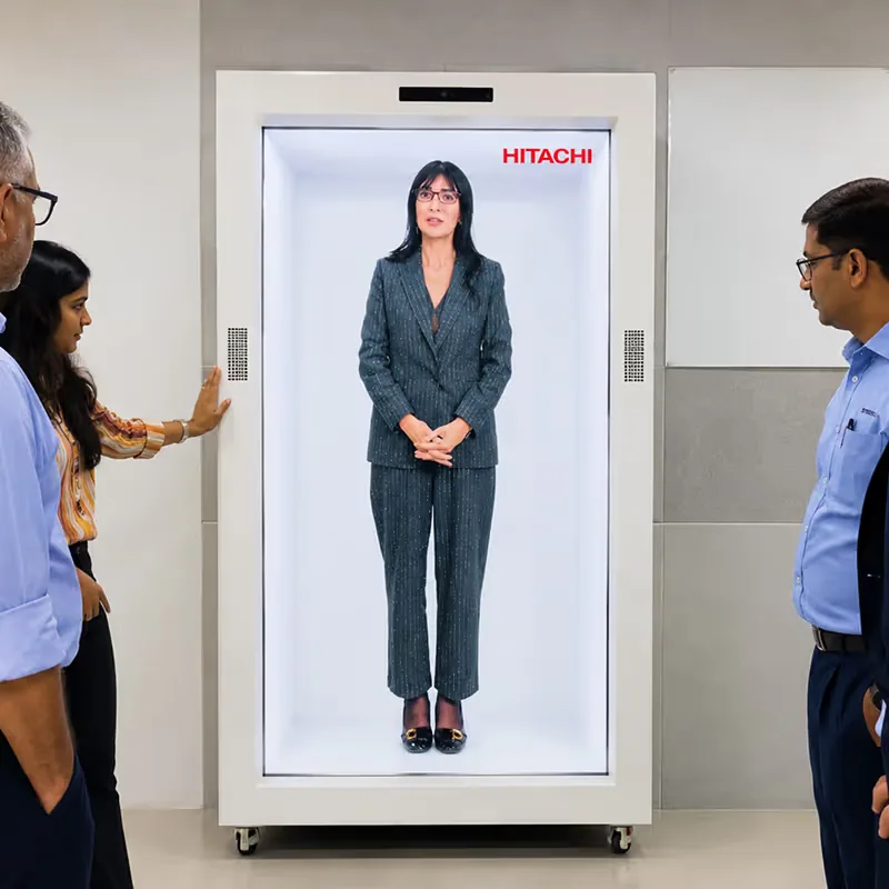 Delegates interacting with the HoloBox911 holographic display unit in a lobby area at Hitachi's company event in New Delhi